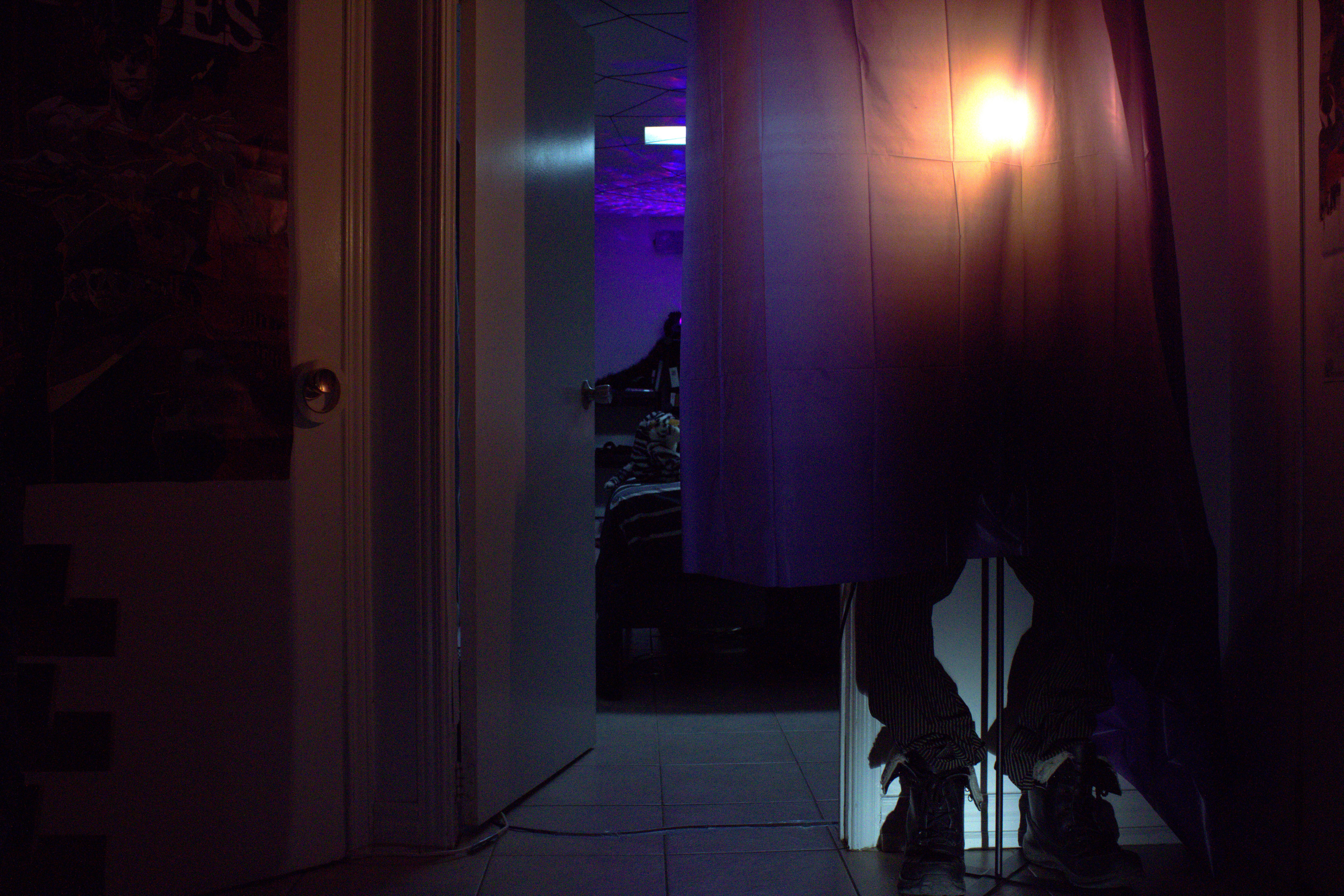 A figure with only its shoes visible, hidden behind a plastic curtain